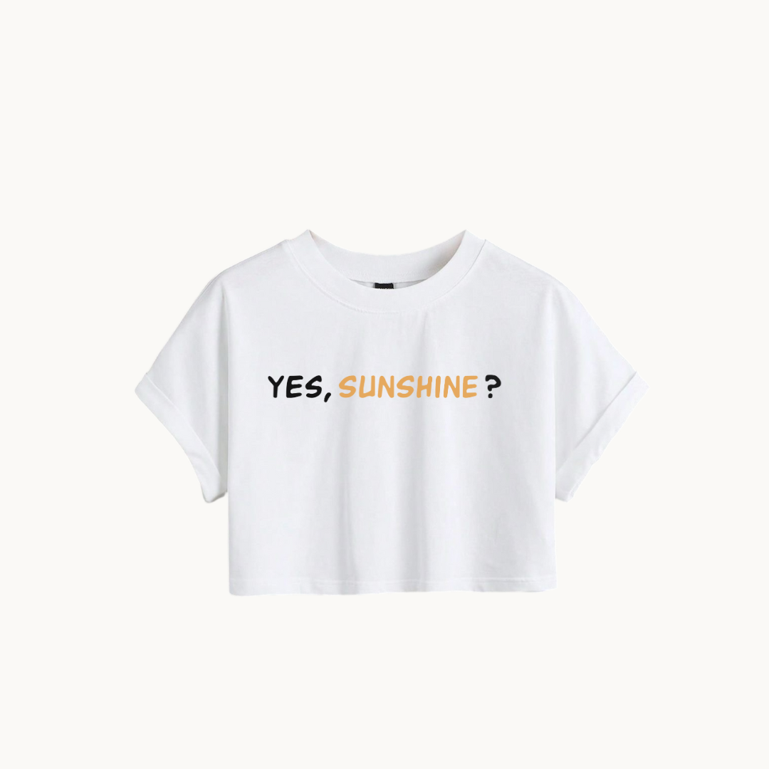 A WHITE cropped T-shirt with the phrase "YES, SUNSHINE?" printed in bold text on the front. The word "YES," is in white, and "SUNSHINE?" is in a warm yellow-orange color-SKULLMASK