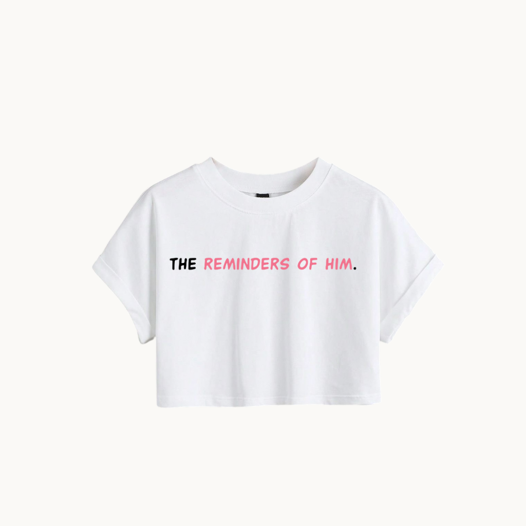 "White cropped t-shirt with the text 'THE REMINDERS OF HIM.' in bold black and pink font. - SKULLMASK
