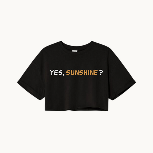 A black cropped T-shirt with the phrase "YES, SUNSHINE?" printed in bold text on the front. The word "YES," is in white, and "SUNSHINE?" is in a warm yellow-orange color.- SKULLMASK